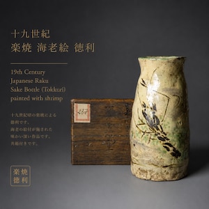 Könnte beinhalten: Eine japanische Raku-Sake-Flasche (Tokkuri) aus dem 19. Jahrhundert, bemalt mit einem Garnelen-Design. Die beige Keramikflasche hat eine strukturierte Oberfläche und einen grünen Rand. Neben der Flasche befindet sich eine Holzkiste mit einem Etikett.