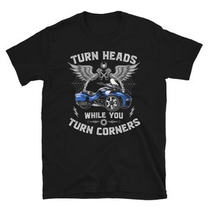 May include: Black t-shirt with a graphic of a blue three-wheeled motorcycle and the text "Turn Heads While You Turn Corners".
