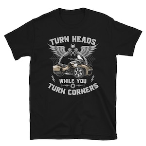 May include: Black t-shirt with a white graphic of a three-wheeled motorcycle with the text "Turn Heads While You Turn Corners".