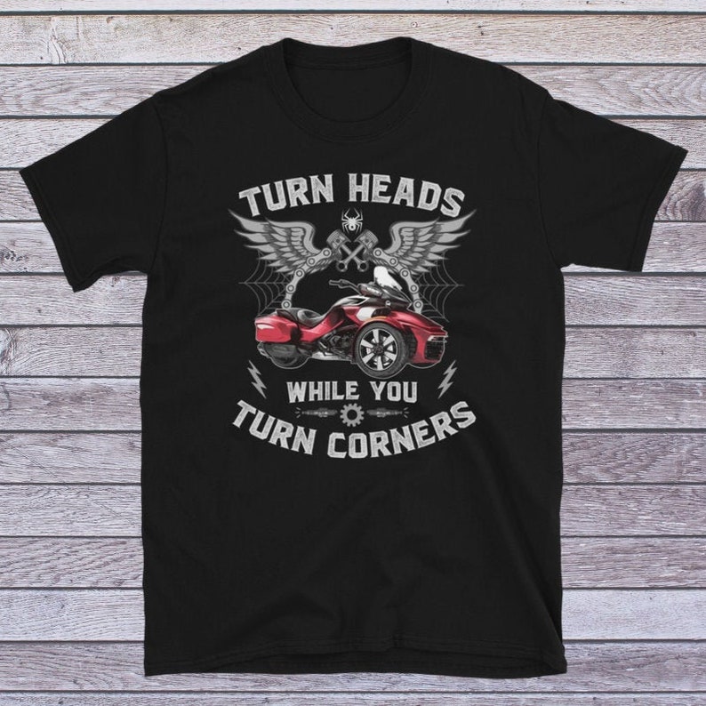 May include: Black t-shirt with a red, white, and gray graphic of a motorcycle with wings and the text "Turn Heads While You Turn Corners".
