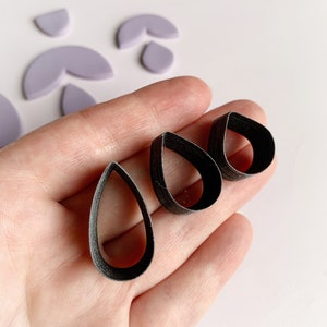 May include: Three black teardrop-shaped cookie cutters of different sizes.