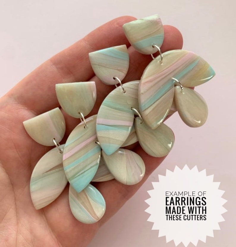 May include: A pair of handmade earrings with a marbled design in shades of blue, green, and pink. The earrings are made with polymer clay and have a delicate, feminine look. "EXAMPLE OF EARRINGS MADE WITH THESE CUTTERS" is written on a white starburst.