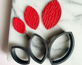 May include: Three red leaf-shaped polymer clay earrings and three black leaf-shaped polymer clay earring moulds.