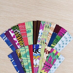 May include: A collection of rectangular paper strips arranged in a fan shape, featuring a variety of colorful patterns including floral prints, geometric shapes, solid colors, heart motifs, and abstract designs in shades of pink, green, blue, and brown.