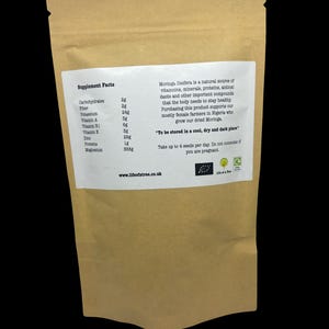 Puede incluir: Una bolsa de papel marr&oacute;n con una etiqueta blanca que enumera los datos nutricionales de las semillas de Moringa Oleifera. La etiqueta incluye una descripci&oacute;n del producto e instrucciones de almacenamiento y consumo. La direcci&oacute;n del sitio web "www.lifeofatree.co.uk" est&aacute; impresa en la parte inferior de la etiqueta.