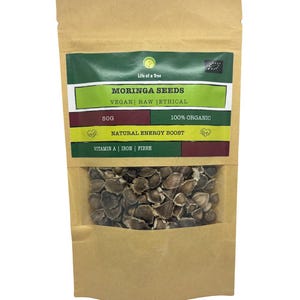 Puede incluir: Una bolsa de papel marr&oacute;n con una etiqueta verde y roja que dice "Moringa Seeds Vegan Raw Ethical 50g 100% Organic Natural Energy Boost Vitamin A | Iron | Fibre". La bolsa contiene semillas de moringa marrones.