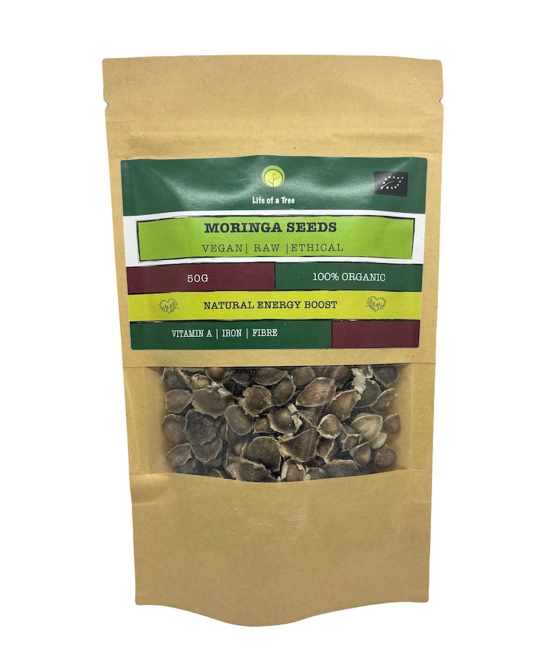 Puede incluir: Una bolsa de papel marr&oacute;n con una etiqueta verde y roja que dice "Moringa Seeds Vegan Raw Ethical 50g 100% Organic Natural Energy Boost Vitamin A | Iron | Fibre". La bolsa contiene semillas de moringa marrones.