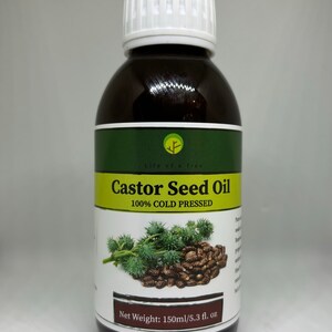 Op de afbeelding: Een bruine fles Castor Seed Oil met een witte dop. Het etiket bevat de tekst "Castor Seed Oil 100% COLD PRESSED" en een afbeelding van ricinusbonen. De fles bevat 150 ml.