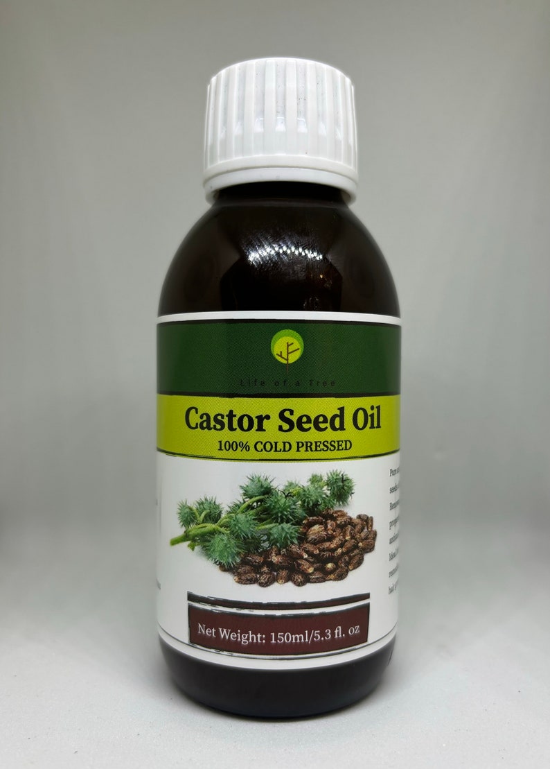 Op de afbeelding: Een bruine fles Castor Seed Oil met een witte dop. Het etiket bevat de tekst "Castor Seed Oil 100% COLD PRESSED" en een afbeelding van ricinusbonen. De fles bevat 150 ml.