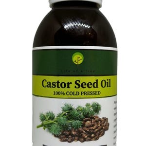 Op de afbeelding: Een donkerbruine fles Castor Seed Oil met een witte dop. Het etiket heeft groene en gele secties met de tekst "Castor Seed Oil 100% COLD PRESSED". Het nettogewicht is 150 ml.