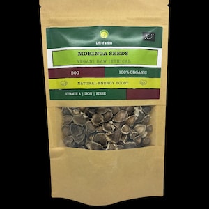 Puede incluir: Una bolsa de papel marr&oacute;n con una ventana transparente que muestra semillas de moringa. La bolsa tiene una etiqueta que dice "Life of a Tree Moringa Seeds Vegan Raw Ethical 50g 100% Organic Natural Energy Boost Vitamin A Iron Fibre".