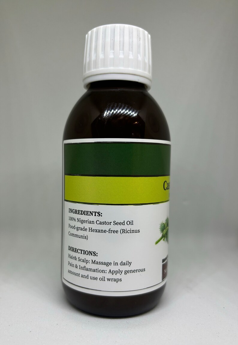 Op de afbeelding: Een donkerbruine fles ricinusolie met een witte dop. Het etiket bevat tekst over ingredi&euml;nten en gebruiksaanwijzingen. De fles bevat 100% Nigeriaanse ricinusolie.