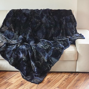 May include: A plush throw blanket in a dark blue and green colour scheme. The blanket is made of faux fur and has a soft, luxurious feel.