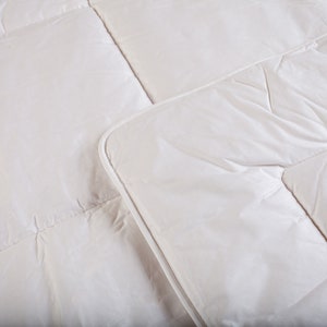 May include: A white down comforter with a quilted pattern. The comforter is made of soft, breathable fabric and is designed to provide warmth and comfort.