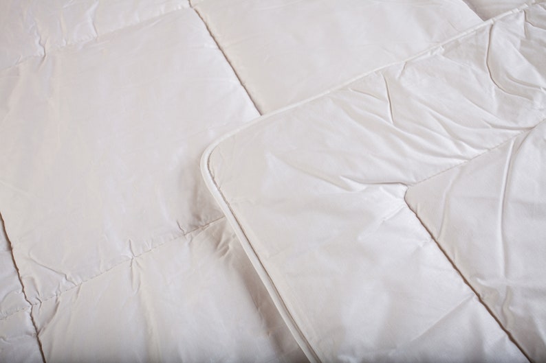 May include: A white down comforter with a quilted pattern. The comforter is made of soft, breathable fabric and is designed to provide warmth and comfort.