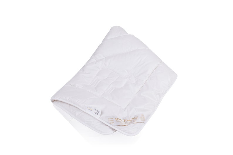 May include: White quilted duvet insert with a white label that says "Mama's Nest" in gold lettering.