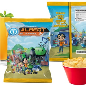 May include: A party-themed image featuring a bag of chips with the text "ALBERT IS TURNING 3". The bag has a cartoon design with characters and a dinosaur. A glass of orange juice and a red bowl of chips are also present. The back of the bag says "THANK YOU FOR COMING TO MY BIRTHDAY".