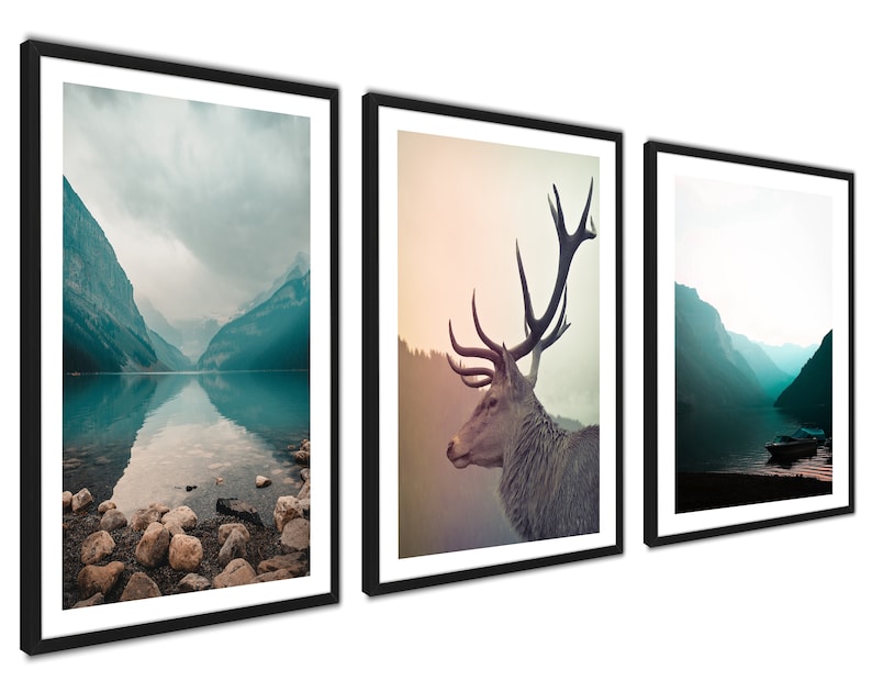 May include: A set of three framed prints featuring nature scenes. The first print shows a mountain lake with a misty sky. The second print shows a deer with large antlers. The third print shows a mountain lake with a boat on the water.