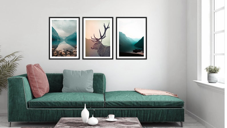 May include: Three framed landscape photographs with a mountain lake and a deer in the middle.