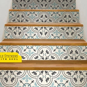Op de afbeelding: Een set blauwe en grijze gepatroneerde tegel stickers voor trappen. De stickers zijn gerangschikt in een herhalend patroon van gestileerde bladeren en bloemen. De tekst "TILE STICKERS WITH SOUL" is zichtbaar in de afbeelding.