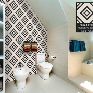 Op de afbeelding: Zwart-witte geometrische tegel stickers voor een badkamer. De stickers zijn in een ruitpatroon en worden op een witte muur geplakt. De tekst op de sticker luidt "Peel & Stick - Adhesive Wall Tile Sticker".