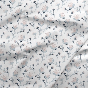 Könnte beinhalten: Ein weißer Stoff mit einem sich wiederholenden Muster aus stilisierten rosa und blauen Blumen. Die Blumen haben einen zarten, handgezeichneten Look.