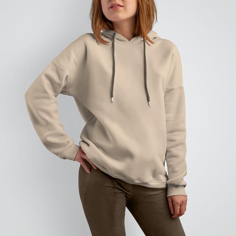 K&ouml;nnte beinhalten: Ein hellbeiger Hoodie mit einer Kapuze mit Kordelzug. Der Hoodie hat lange &Auml;rmel und eine lockere Passform.