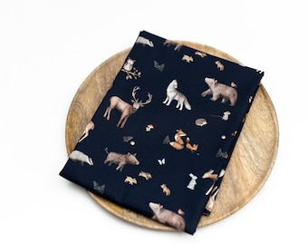 May include: A dark blue fabric with a repeating pattern of woodland animals, including a deer, wolf, bear, fox, and badger. The fabric is on a wooden plate.