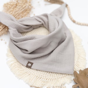 Könnte beinhalten: Ein hellgraues Bandana mit einem braunen Stern in der Mitte. Das Bandana ist gefaltet und auf einem weißen Hintergrund mit Fransenbesatz abgebildet.