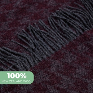 Puede incluir: Primer plano de una bufanda de lana color burdeos y gris con flecos. La bufanda está hecha de 100% lana de Nueva Zelanda.