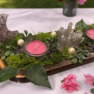 May include: A decorative wooden tray with a crescent moon, crystals, candles, and greenery. The tray features two pink candles in glass holders, faux pearls, and a variety of plants. The arrangement is accented with pink roses.