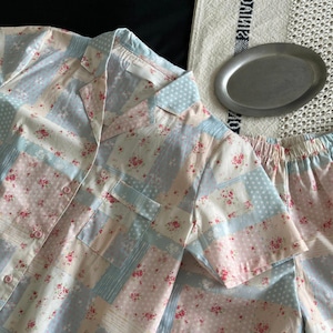 Peut inclure: Un ensemble pyjama bleu pastel et rose avec un motif patchwork floral. Le haut a un col boutonné et des manches courtes. Le short a une taille élastique.