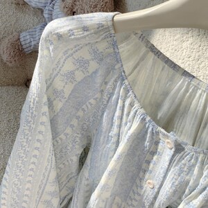 May include: A white ceramic mug with a black handle and the text "But First, Coffee" in a black, handwritten-style font. The mug is on a white surface.