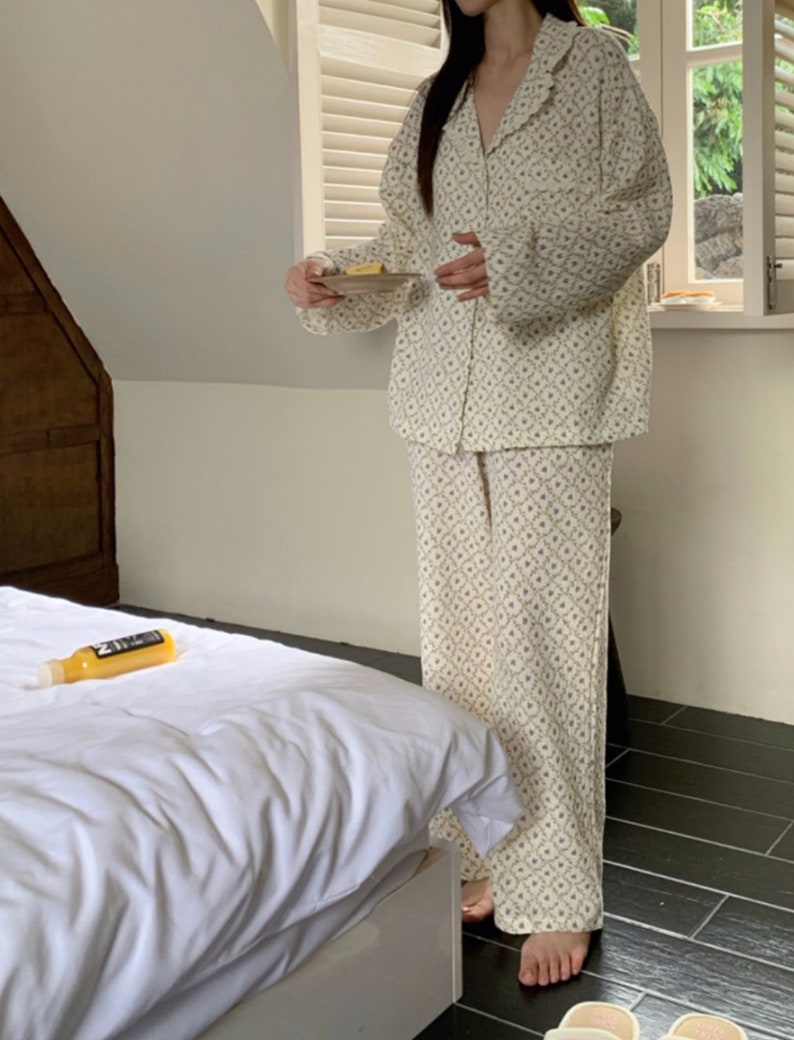 May include: A white pajama set with a floral pattern. The top has a collar and long sleeves. The pants are long and have a straight leg.
