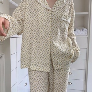 May include: A white and gold floral print pajama set with a ruffled collar and long sleeves.