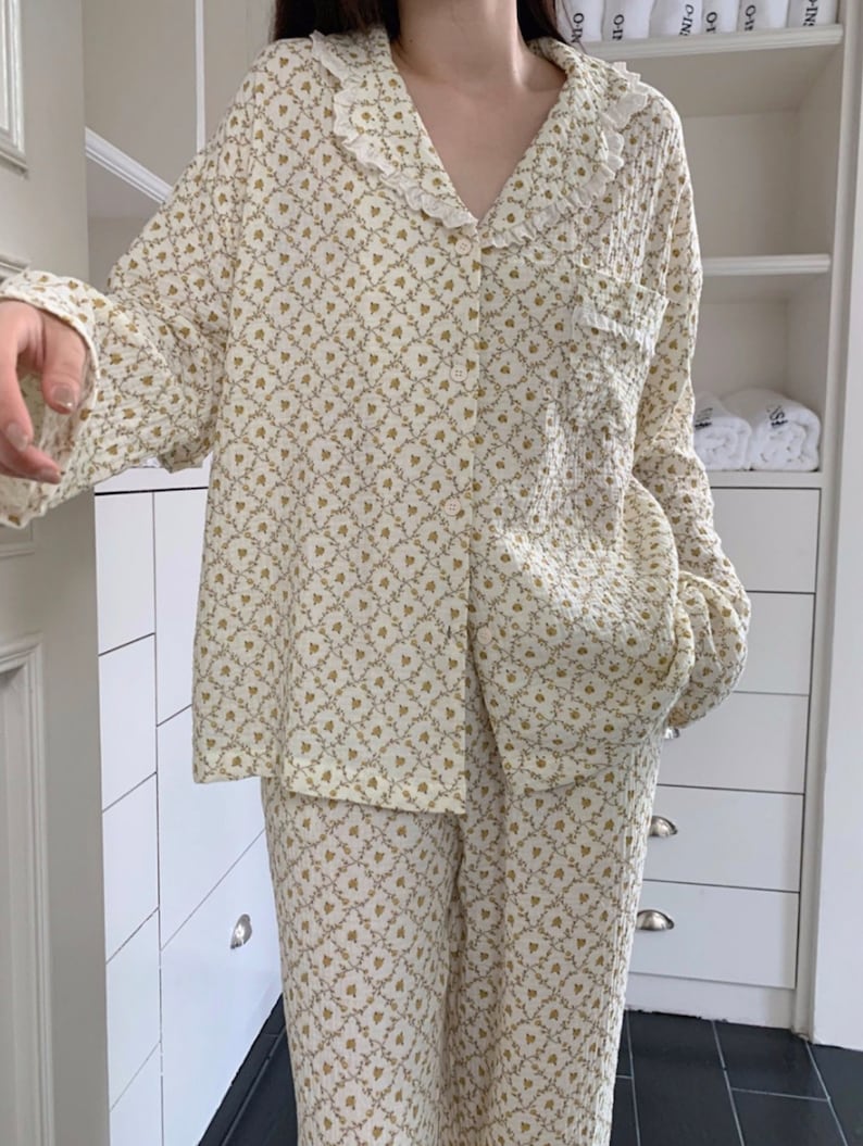 May include: A white and gold floral print pajama set with a ruffled collar and long sleeves.