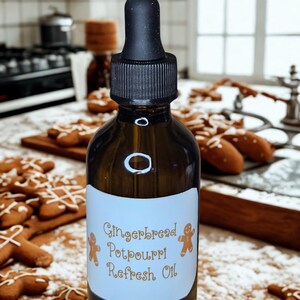 May include: A dark amber glass bottle with a black dropper cap. The label reads "Gingerbread Potpourri Refresh Oil" with gingerbread man illustrations. Gingerbread cookies are scattered around the bottle, suggesting a holiday theme.
