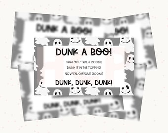 Può includere: Una carta rettangolare con sfondo grigio e un motivo ripetuto di fantasmi bianchi. Il riquadro bianco centrale contiene il testo nero: DUNK A BOO! FIRST YOU TAKE A COOKIE, DUNK IT IN THE TOPPING, NOW ENJOY YOUR COOKIE, DUNK, DUNK, DUNK!