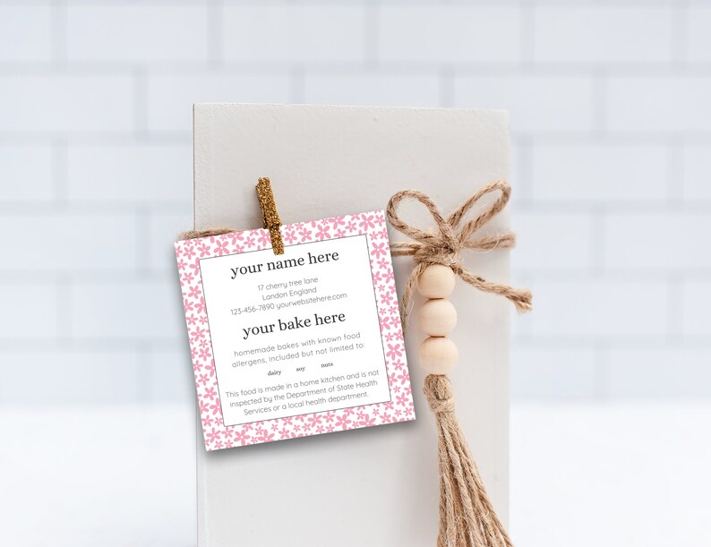 May include: Pink floral patterned card with the text "your name here", "17 cherry tree lane", "London England", "123-456-7990 yourwebster.com", "your bake here", "homemade bakes with known food allergens, included but not limited to", "dairy", "soy", "wheat", "This food is made in a home kitchen and is not inspected by the Department of State Health Services or a local health department".