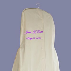 Peut inclure: Housse de vêtement crème avec un cintre, une fermeture à boutons et le nom "Jenna K Dart" et la date "05 mai 2016" en écriture violette. Conçue pour protéger les vêtements.
