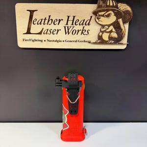 May include: A red fire extinguisher with a black mounting bracket and a decorative emblem. The image also features a wooden sign with the text "Leather Head Laser Works" and a cartoon squirrel wearing a firefighter's helmet.