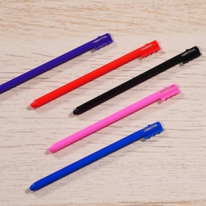 May include: Five stylus pens in different colors: blue, red, black, pink, and blue. The pens are all the same size and shape, with a pointed tip and a small, rounded cap.