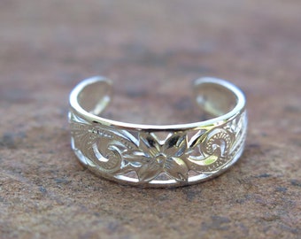 May include: A silver toe ring with a floral design. The ring is made of sterling silver and has a delicate, intricate design.
