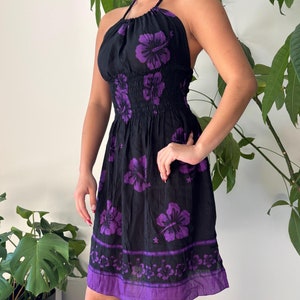 May include: A black halter dress with a purple floral print. The dress has a fitted bodice and a flowy skirt.