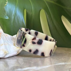 Può includere: Un set di tre tazze in ceramica con finitura opaca e macchiettata. Le tazze sono nei toni del crema, grigio chiaro e grigio scuro. Ogni tazza ha un design semplice e minimalista.