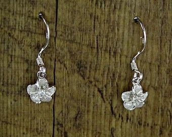 Può includere: Un paio di orecchini pendenti in argento con un design a forma di fiore. I fiori sono fatti di piccoli cristalli trasparenti.