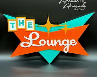 May include: A retro-style sign with the words "THE Lounge" in white lettering. The sign features a starburst design in orange, teal, and gold, with the text "Atomic Avocado Designs" in the upper right corner.