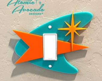 May include: A turquoise, orange, and yellow mid-century modern light switch cover with a starburst design.  Atomic Avocado Designs® is printed on the top of the cover.