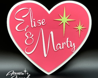 May include: Pink heart-shaped sign with white lettering that reads "Elise & Marty" and two yellow stars.
