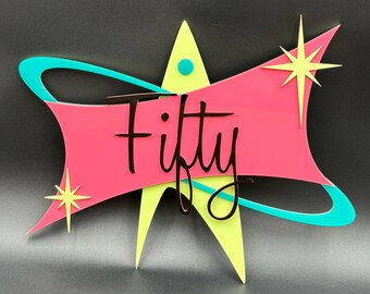 May include: A pink and yellow starburst design with a turquoise swirl. The word "Fifty" is written in black script on the pink section.